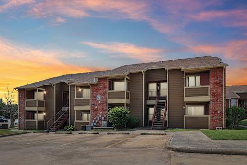 A large apartment complex with a parking lot in front.