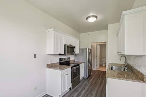A kitchen with white cabinets and a granite countertop.
