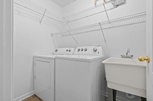 Laundry room with washer dryer and utility sink at Regents Club of Troy Apartments, Troy, Michigan