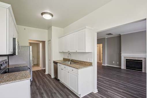 A kitchen with white cabinets and a granite countertop.