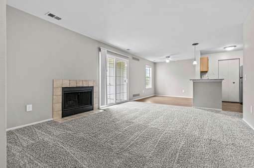 A spacious living room with a fireplace and a grey carpet.