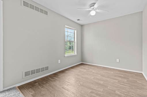 Empty room with a window and a ceiling fan.