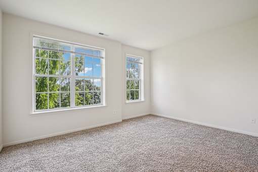 A room with two windows and carpeted floor.