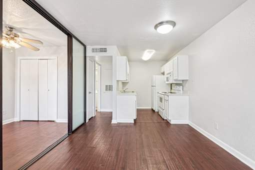 A kitchen with white appliances and wooden floors.