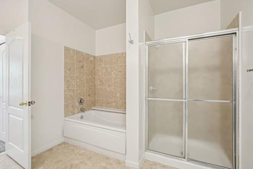 A bathroom with a white tub and shower enclosure.