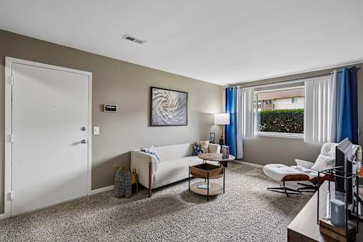 A living room with a white couch and a painting on the wall.