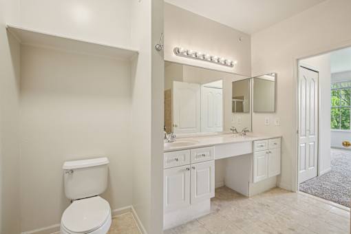 A white bathroom with a toilet, sink, and mirror.