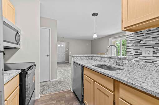 A kitchen with a black dishwasher and a black fridge.