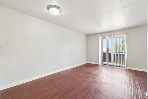 A room with a wooden floor and a window with a metal grate.
