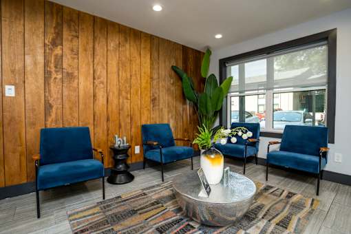 A living room with blue chairs and a wooden wall.