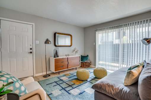 A living room with a grey couch, a mirror, a wooden cabinet, and a rug.