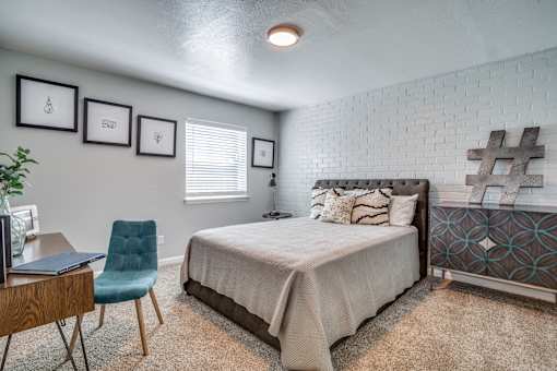 A bedroom with a bed, chair, and pictures on the wall.