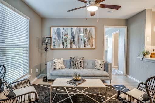 A living room with a grey couch, a coffee table, and a painting on the wall.
