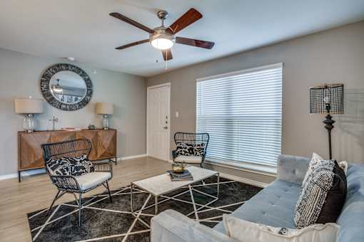 A living room with a ceiling fan and a mirror on the wall.
