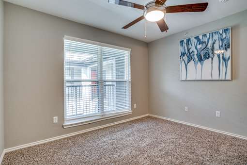 A room with a ceiling fan and a painting on the wall.