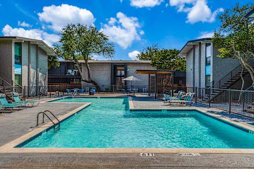A swimming pool surrounded by chairs and buildings.