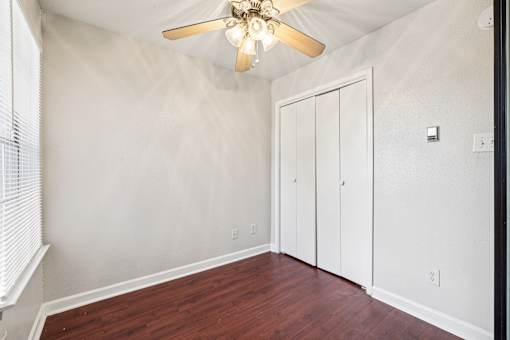 A room with a ceiling fan and a wooden floor.