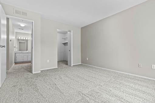 A spacious room with grey carpeting and two doors.