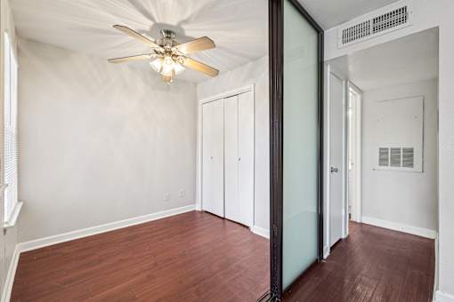 A room with a ceiling fan and wooden floors.