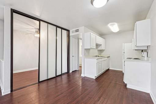 A kitchen with white cabinets and a wooden floor.