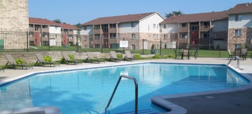 Brighton Cove outdoor pool. Expansive sundeck with lounge chairs. Brighton Cove in the background.