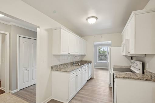 A kitchen with white cabinets and a granite countertop.