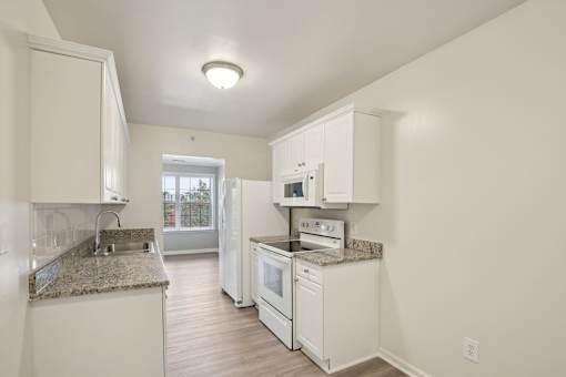 A kitchen with white appliances and cabinets.