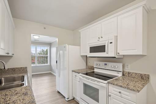 A kitchen with white appliances and cabinets.