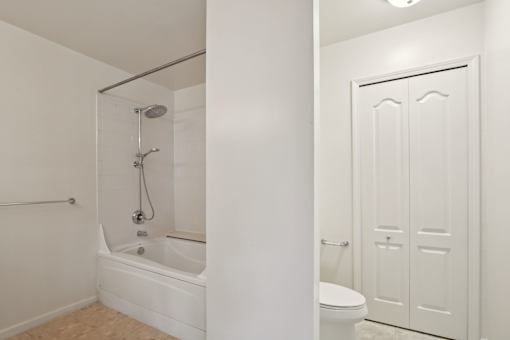 A white bathroom with a tub, toilet and shower.