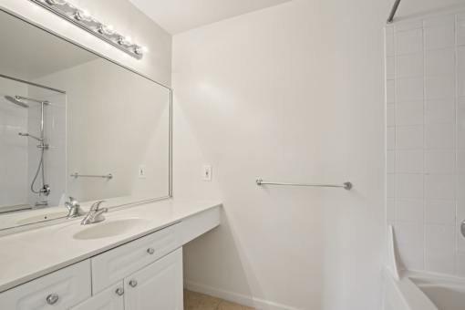 A white bathroom with a sink, mirror, and a shower.