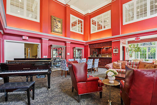 A living room with a piano and red chairs.