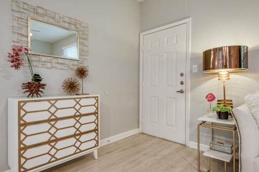 A white door is in a room with a gold and white dresser.