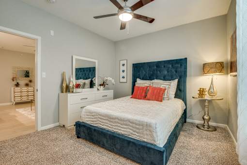A bedroom with a bed, nightstand, and a ceiling fan.