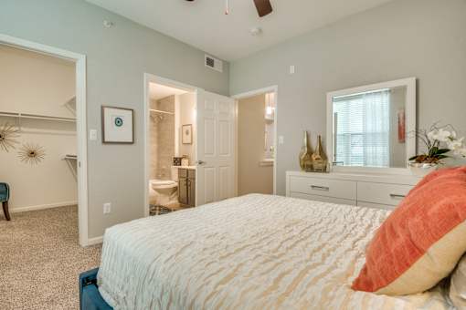 A bedroom with a large bed and a dresser with a mirror.
