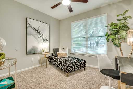A bedroom with a bed, chair, and a painting on the wall.