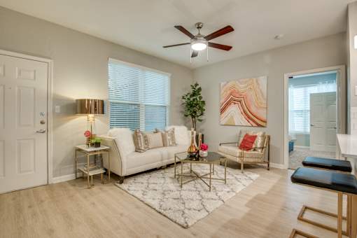 A living room with a white couch, a coffee table, and a ceiling fan.