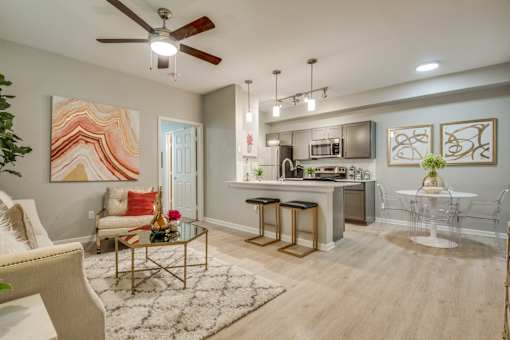 A modern living room with a kitchen area in the background.