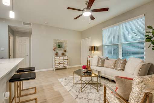 A living room with a white couch, a coffee table, and a ceiling fan.