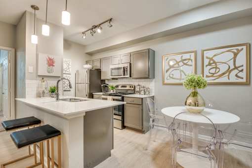 A modern kitchen with a white island and black bar stools.
