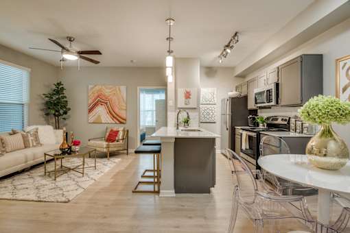 A modern kitchen with a bar stool and a dining table with chairs.
