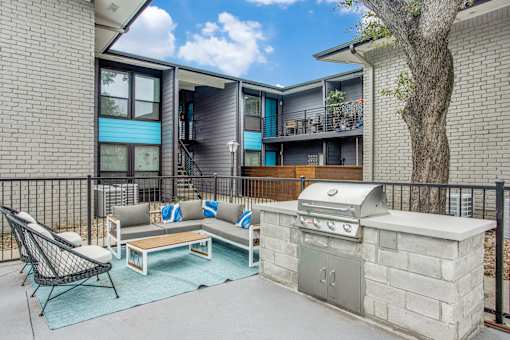 A patio with a grill and a chair.