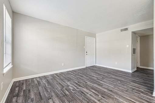 A room with wooden flooring and white walls.
