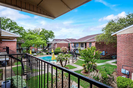 A view from a balcony overlooking a pool and apartment buildings.