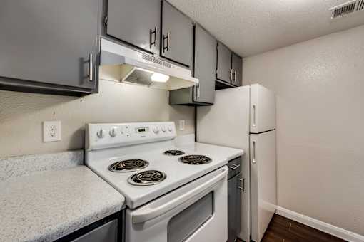 A white stove and oven in a kitchen with a white refrigerator.