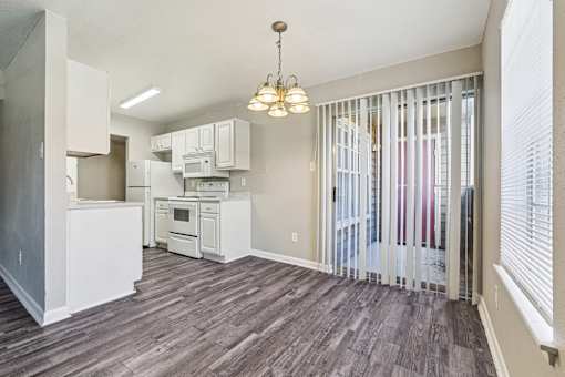 A kitchen with white appliances and wooden floors.