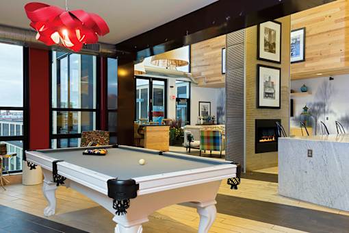 A pool table in a room with a fireplace and a fire burning.