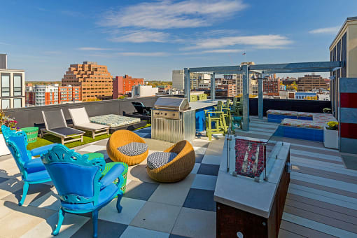 a rooftop terrace with chairs and tables and a city in the background at Ann Arbor City Club, Michigan