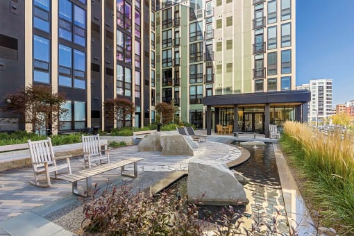 a courtyard with benches and a water feature in front of a tall building at Ann Arbor City Club, Michigan, 48104