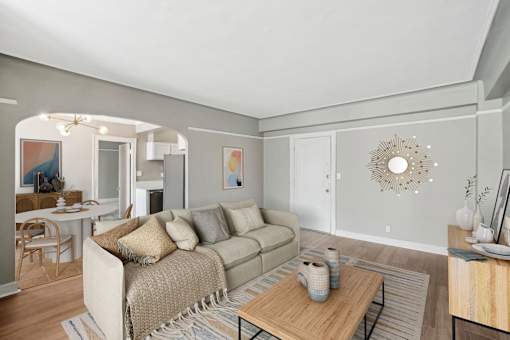 A living room with a couch, coffee table, and a dining table.