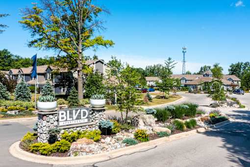a garden area with a sign and a house in the background